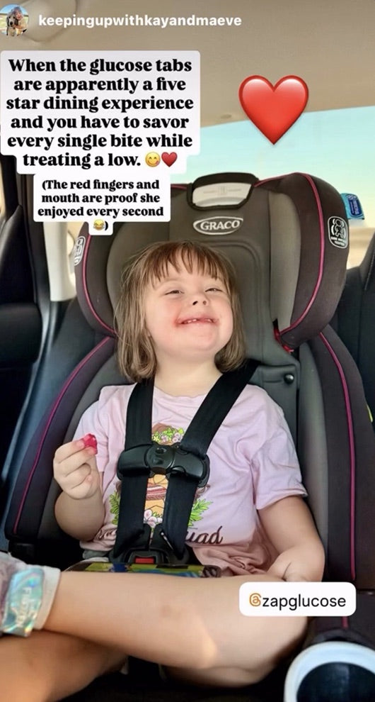 A toddler in a car seat smiling while eating a Zap tablet